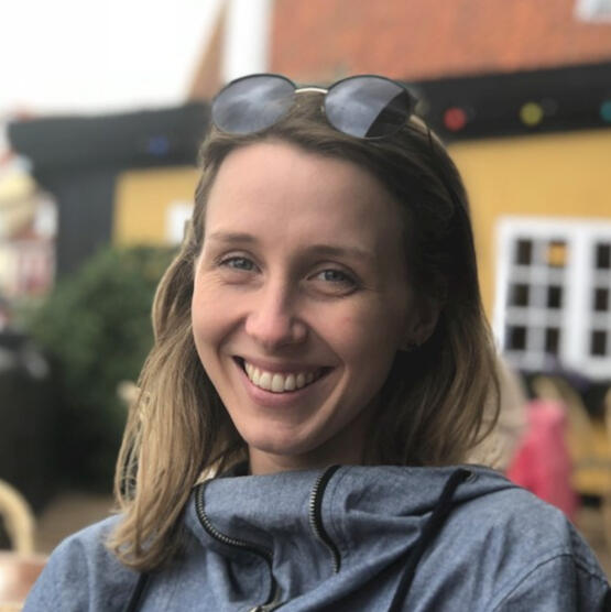 Photo of Alexandra Maccoll Garfinkel sitting outside in Denmark wearing a grey jacket.